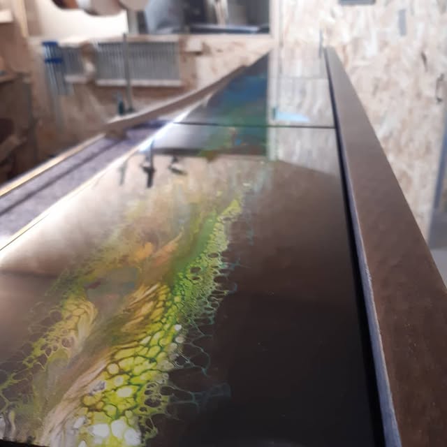 Plateau de la console vu en enfilade, coulée de résine verte et jaune sous le vernis, à l’atelier