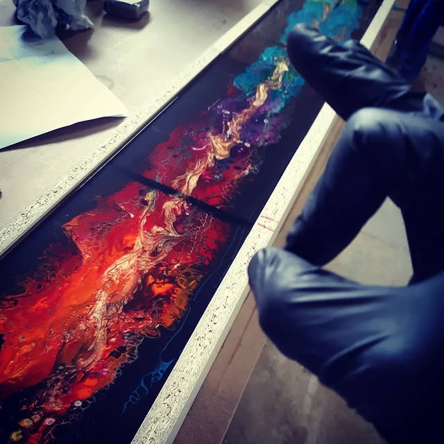 La résine époxy encore liquide, travaillée à la main avec des gants dans le cadre de la façade, à l’atelier