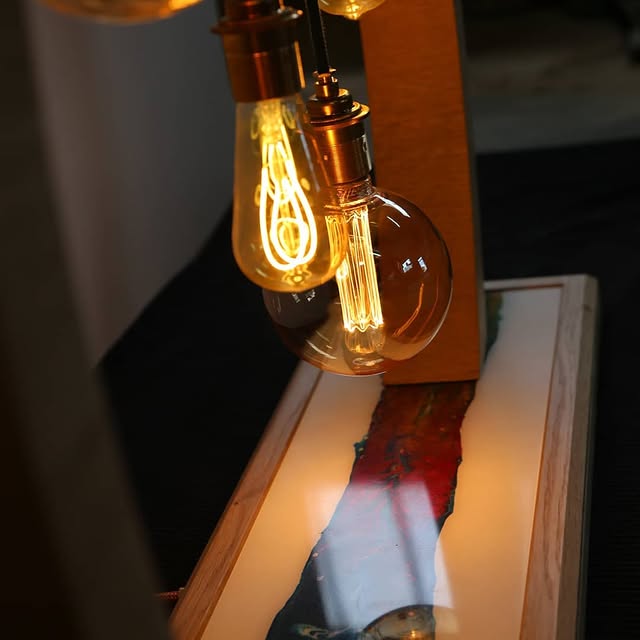 Les ampoules à filament du luminaire allumées dans la pénombre, douilles en laiton sur montant de chêne